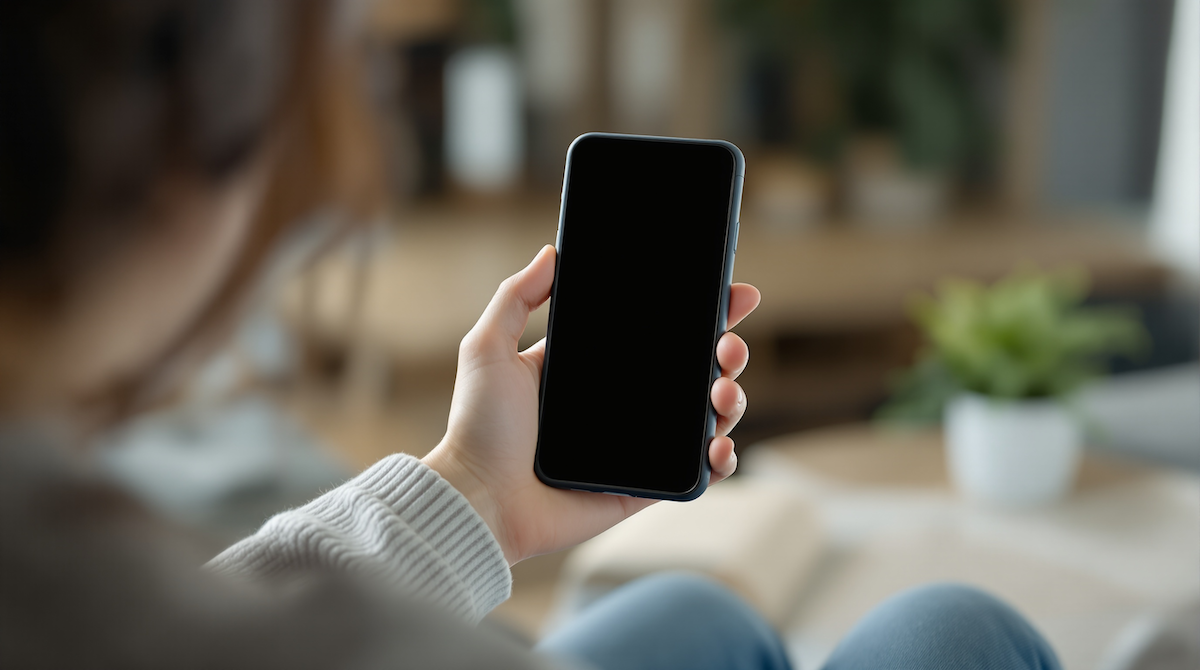 ソファに座る女性が片手でスマートフォンを持っている様子